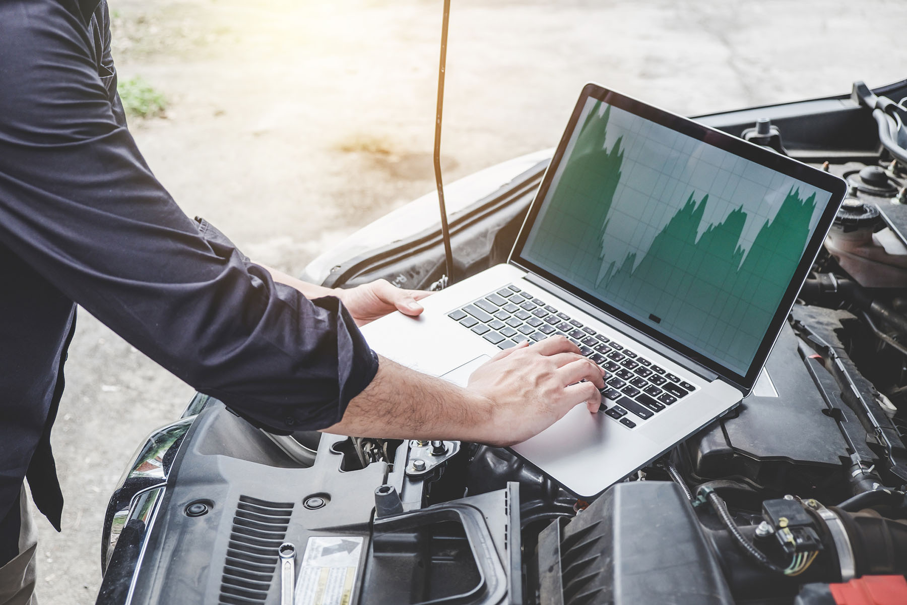 Automobile mechanic repairman checking a car engine with using computer diagnostics while repairing, car service and maintenance.